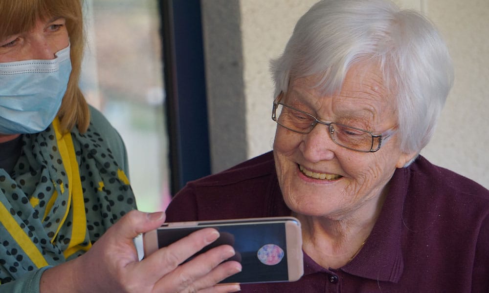 Woman and her carer viewing something on a phone